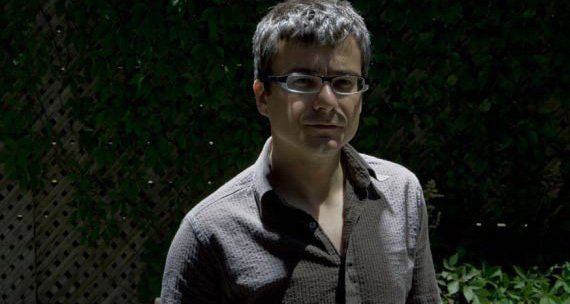 Mark Krupka with glasses, wearing a button-down shirt, looking forward in a dark outdoor setting.