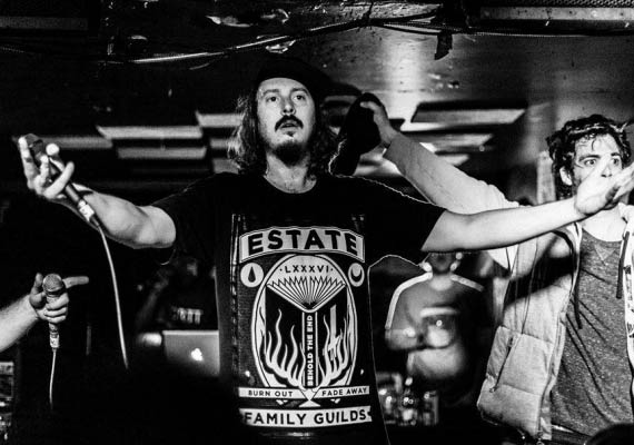 A man wearing a t-shirt that says estate is singing into a microphone.