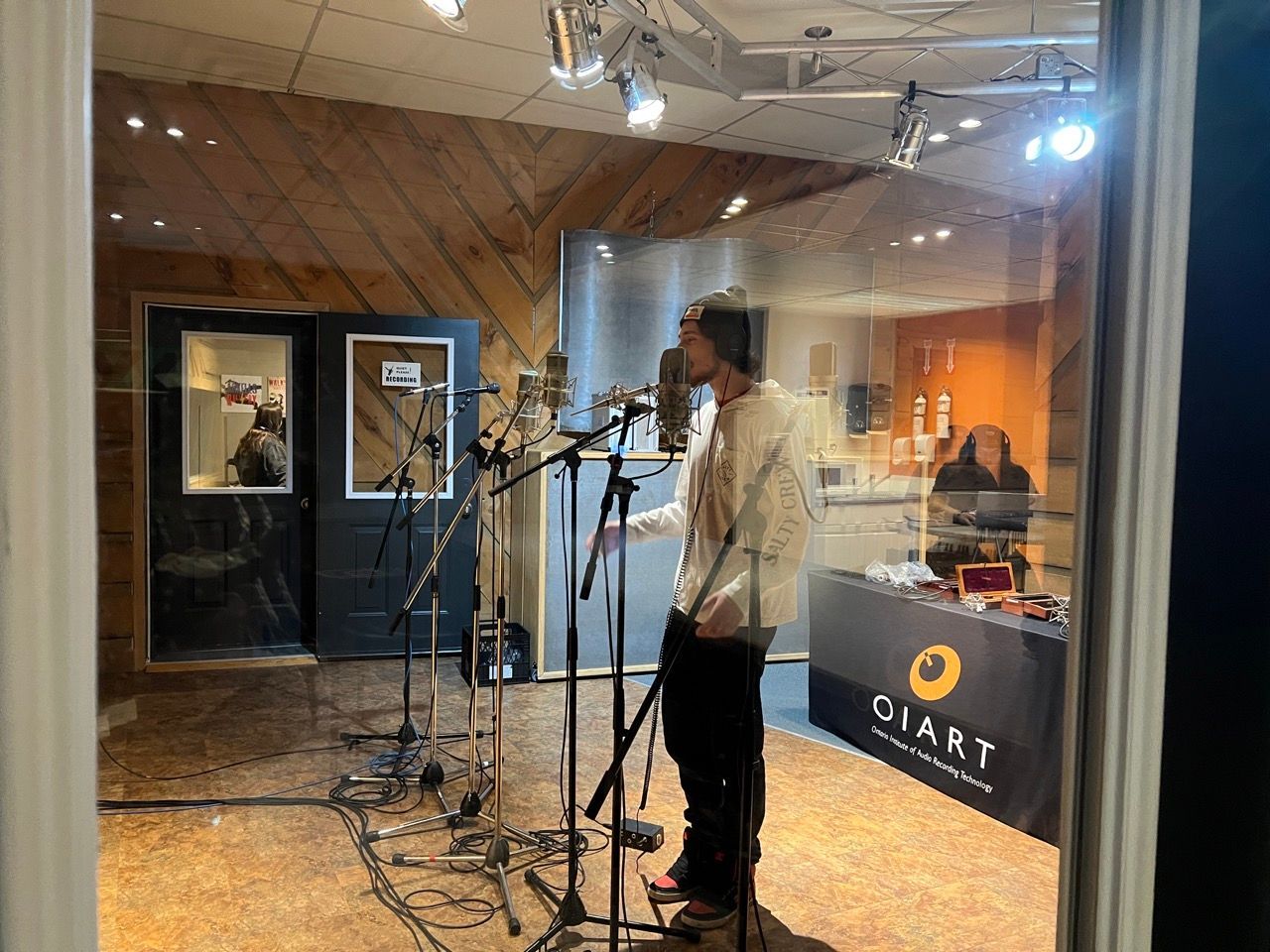 A man is singing into a microphone in a recording studio.