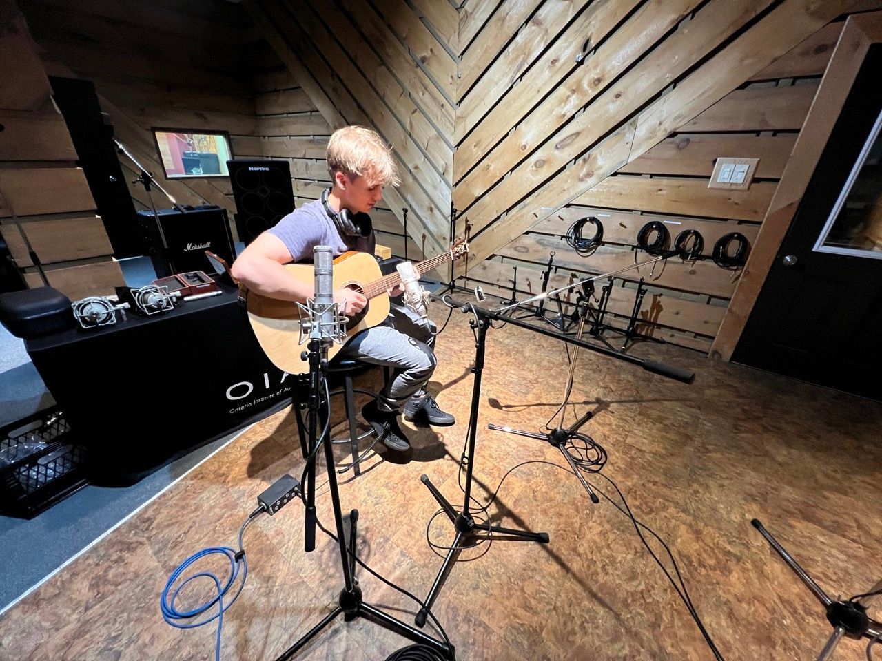 A man is playing an acoustic guitar in a recording studio.