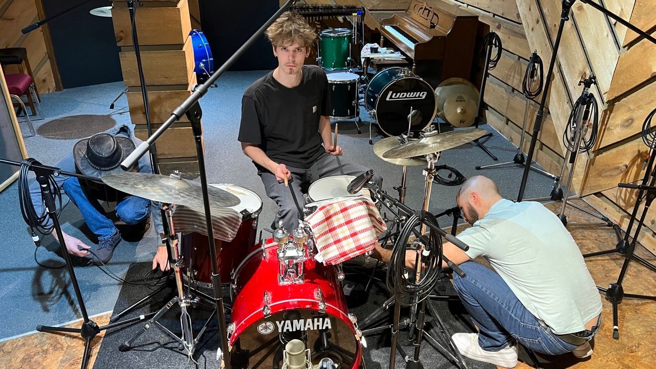 A group of people are playing drums in a room.