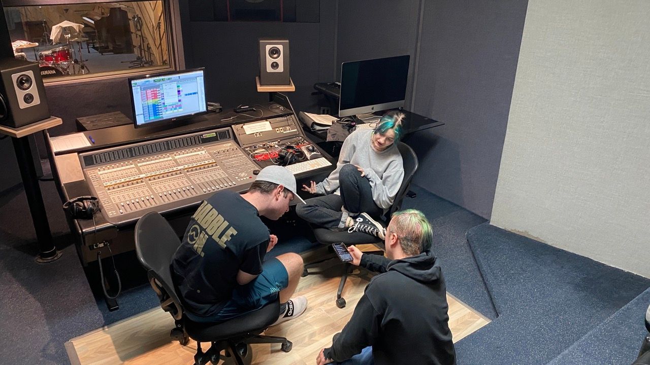 A group of people are sitting in a recording studio.