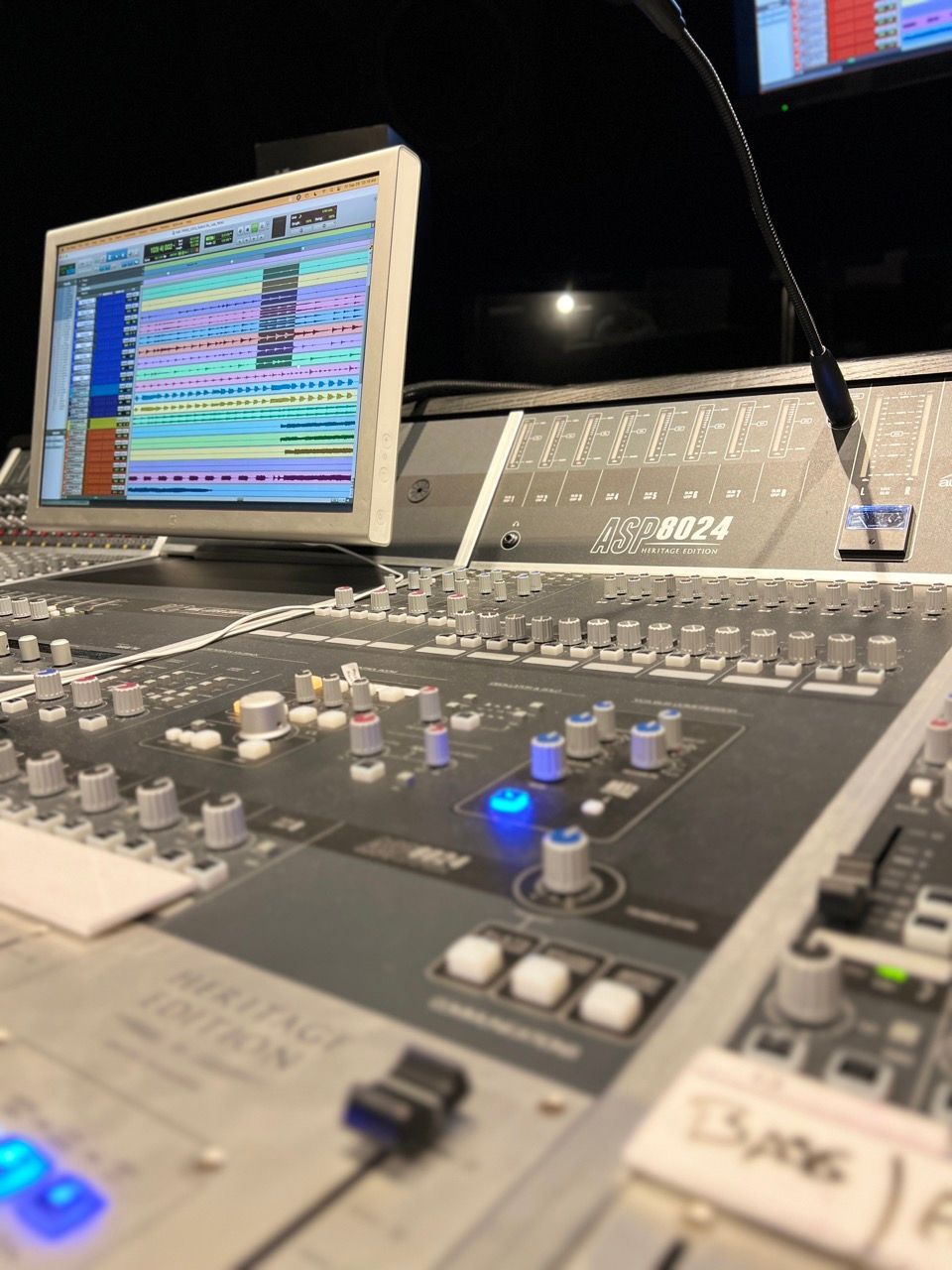 Recording studio mixing console with computer display showing audio tracks.