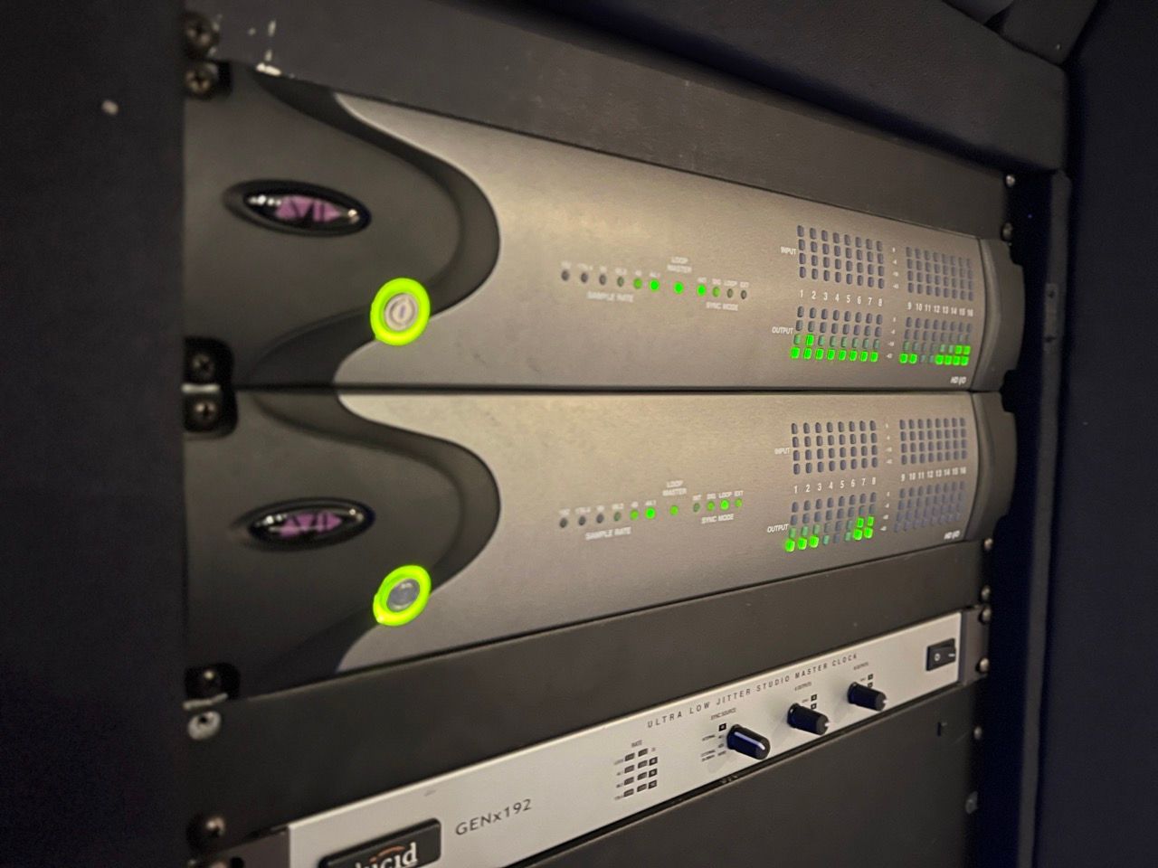 Rack of audio equipment with two gray amplifiers and a silver control panel.