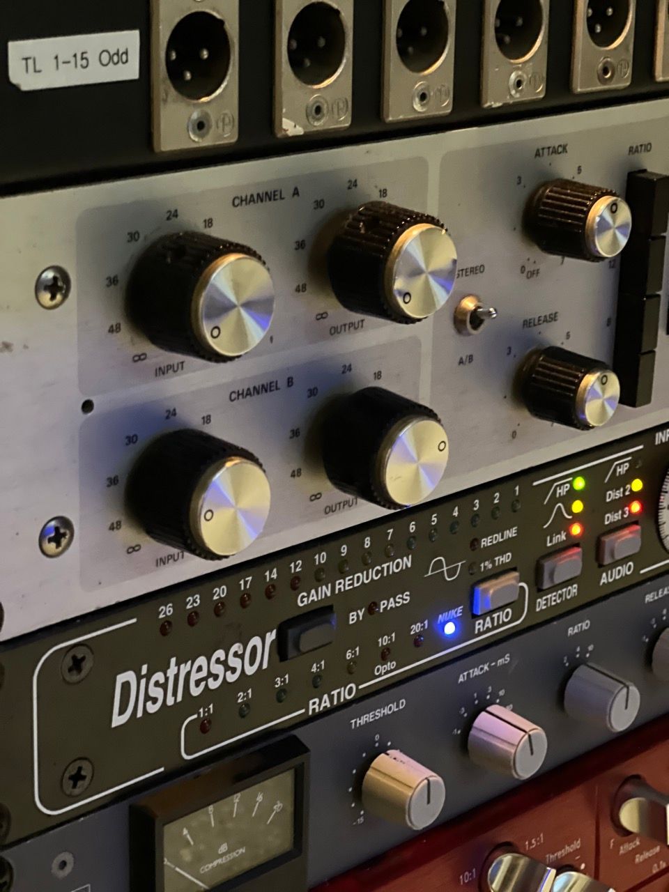 Close-up of audio rack equipment with knobs and meters. Includes a compressor and a channel strip.
