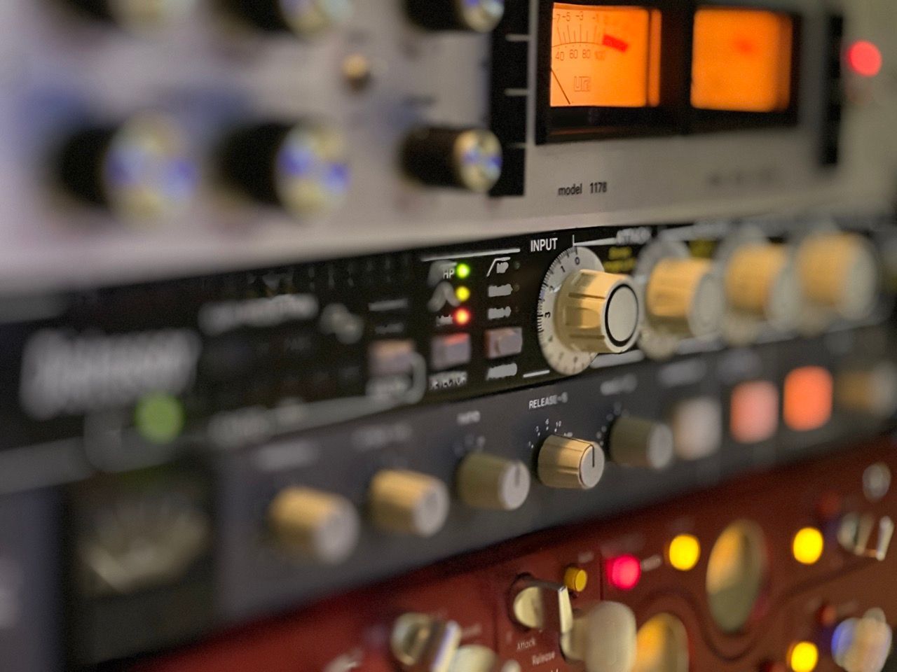 Close-up of audio equipment in a rack, with various knobs, buttons, and meters visible; a sound studio.