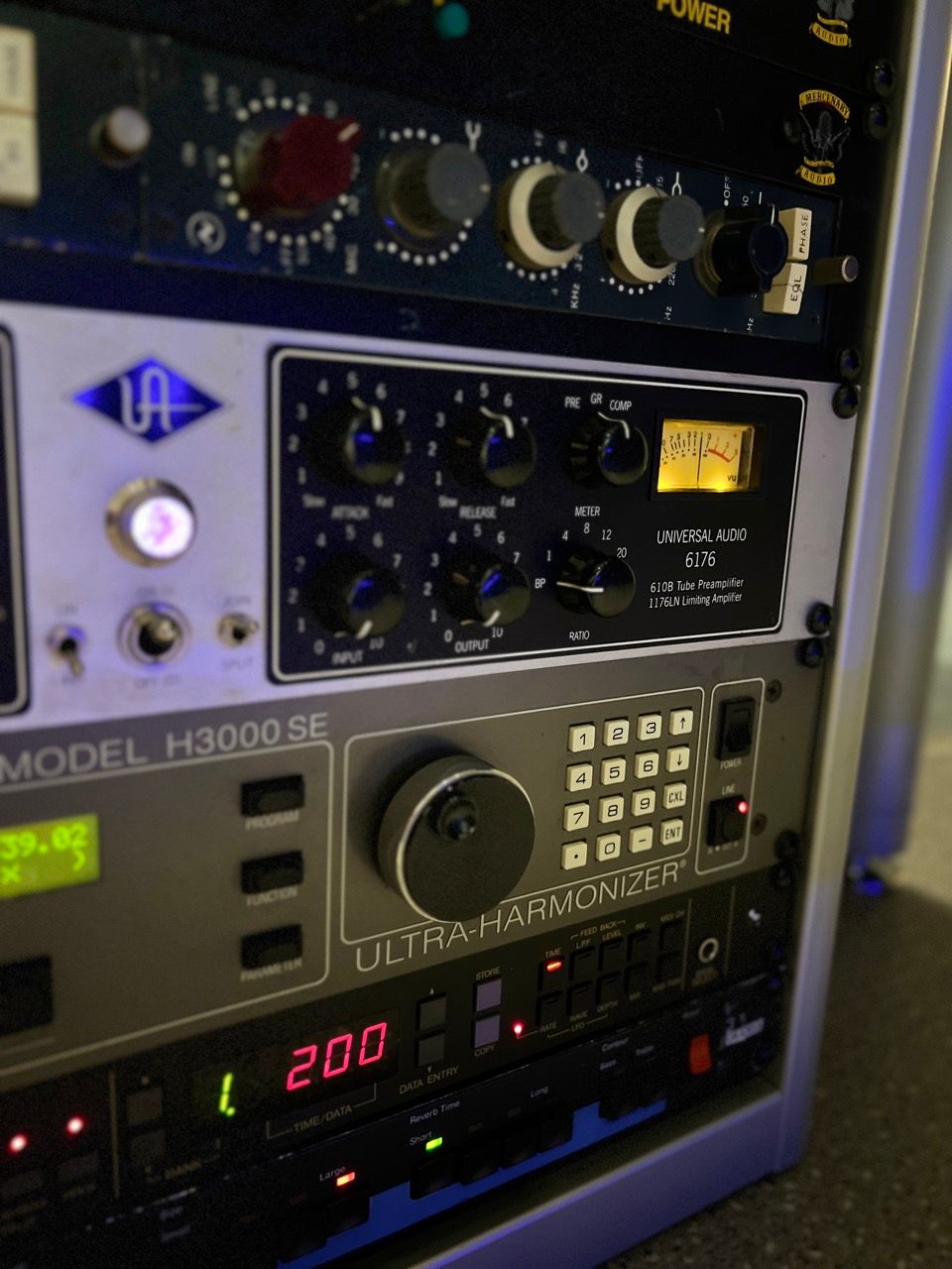 Close-up of a recording studio equipment rack with various audio processing units, including a tube microphone preamp.
