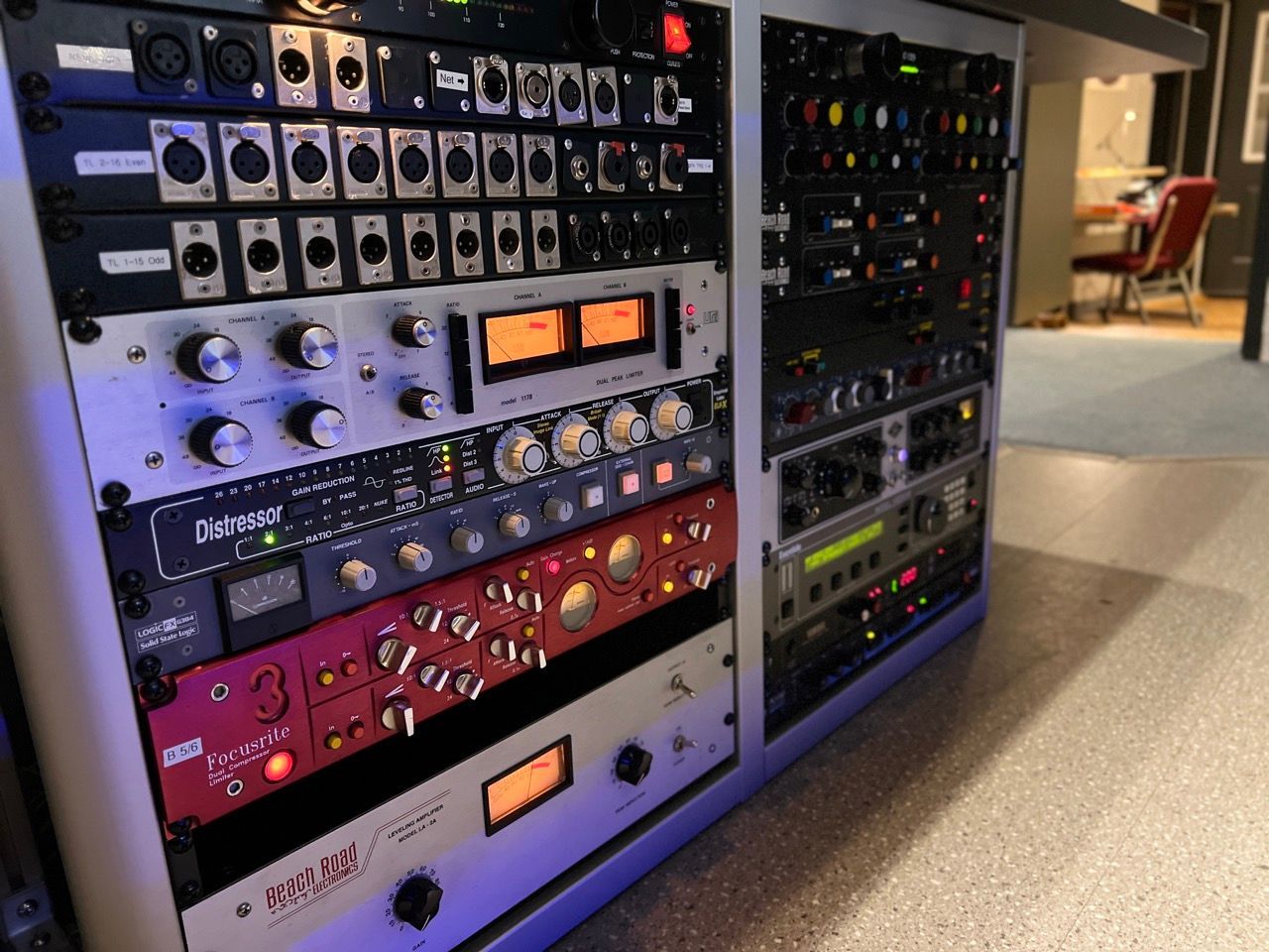 Rack of professional audio recording equipment, including preamps and processors, in a studio setting.