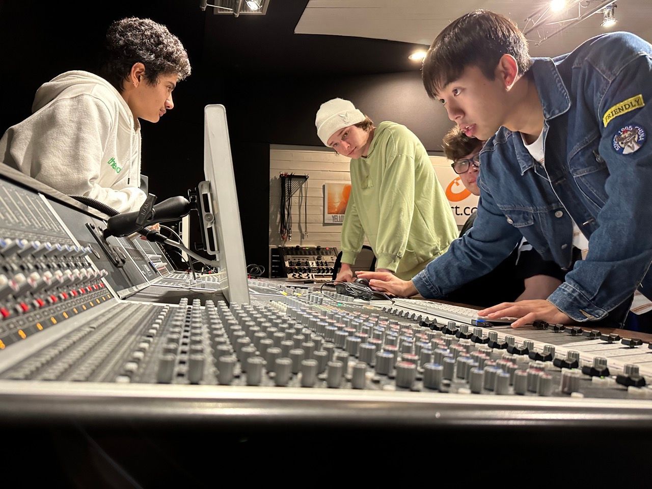 A group of young men are working on a sound board in a recording studio.