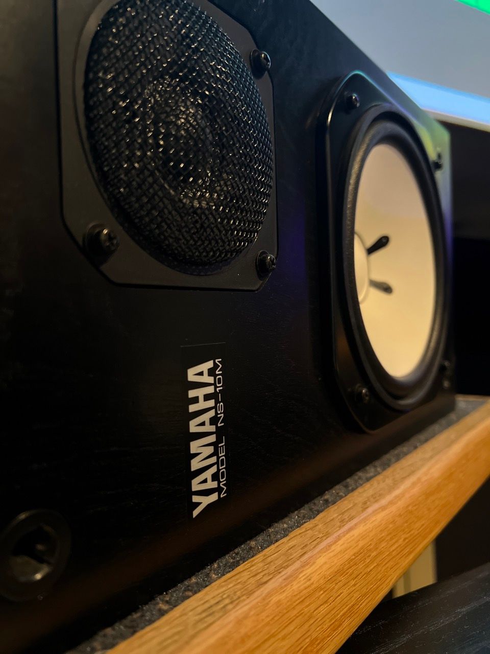 A yamaha speaker is sitting on a wooden shelf