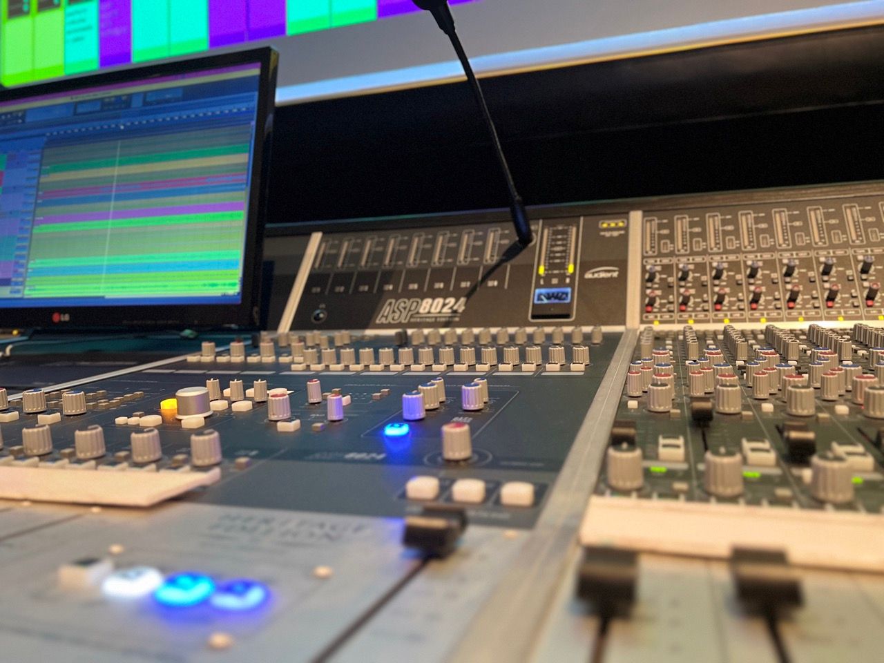 A microphone is sitting on a mixer in front of a computer monitor