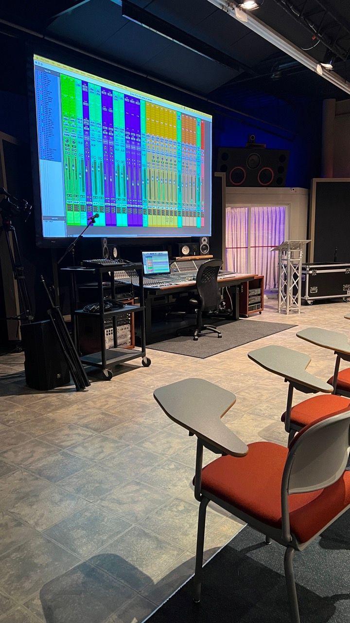 A room with chairs and a large screen on the wall.