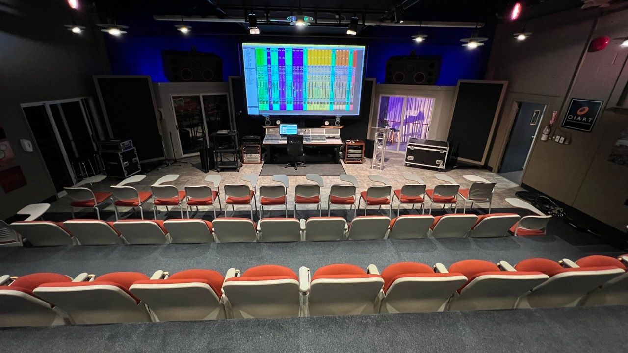 An auditorium with rows of seats and a large screen on the stage.