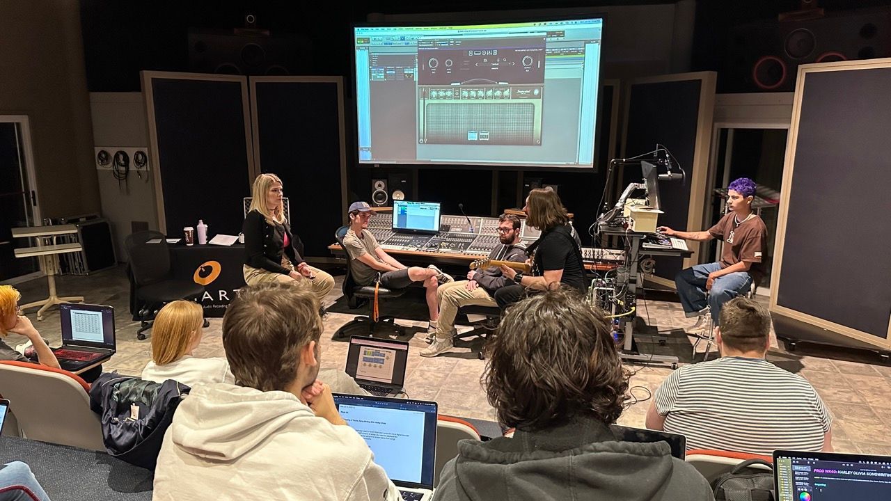 A group of people are sitting in front of a projector screen in a room.