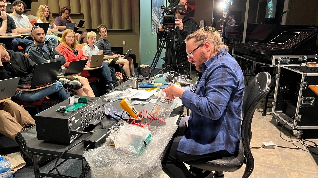 A man is sitting at a desk in front of a group of people.