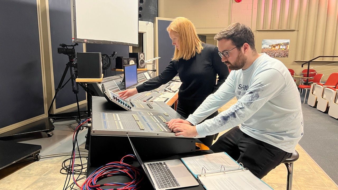 A man and a woman are working on a computer in a room.