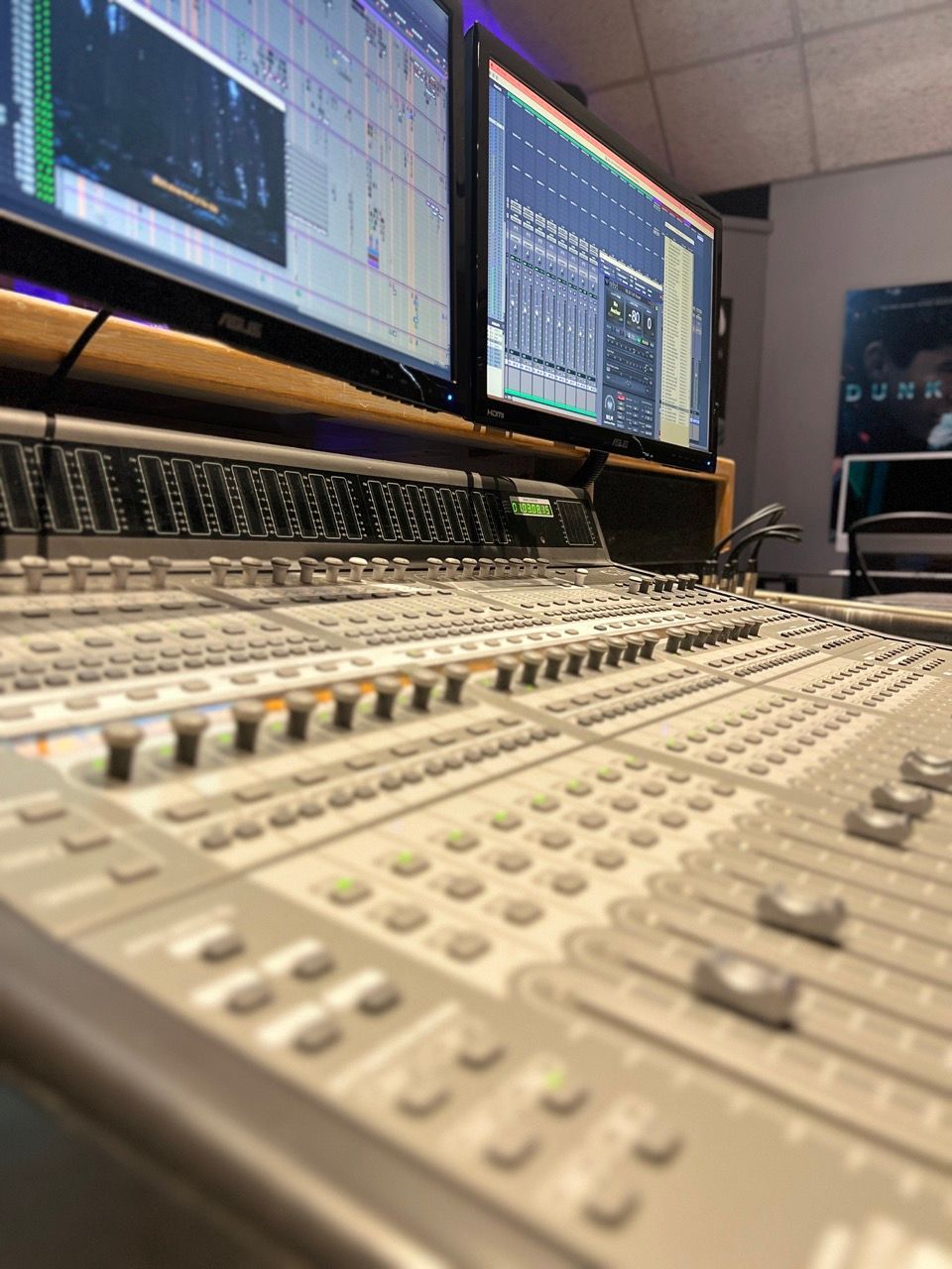 A recording studio with a mixer and two monitors.