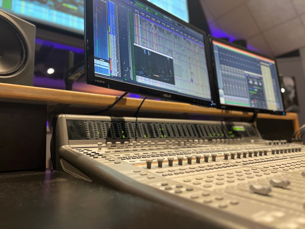 A recording studio with three monitors and a mixer
