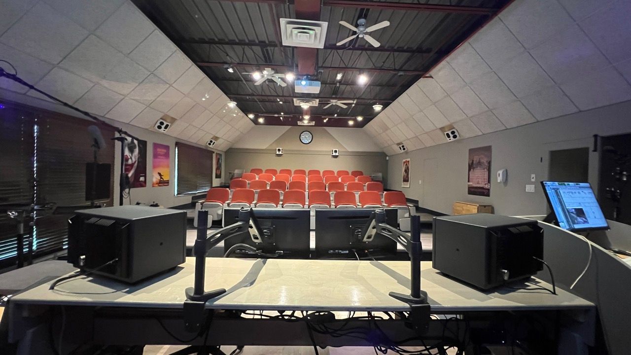 A large auditorium with red seats and projectors