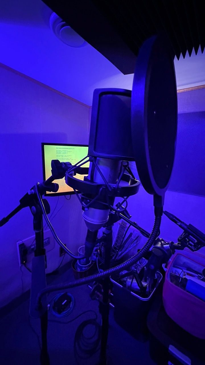 A microphone is sitting in a recording studio with a blue light behind it.