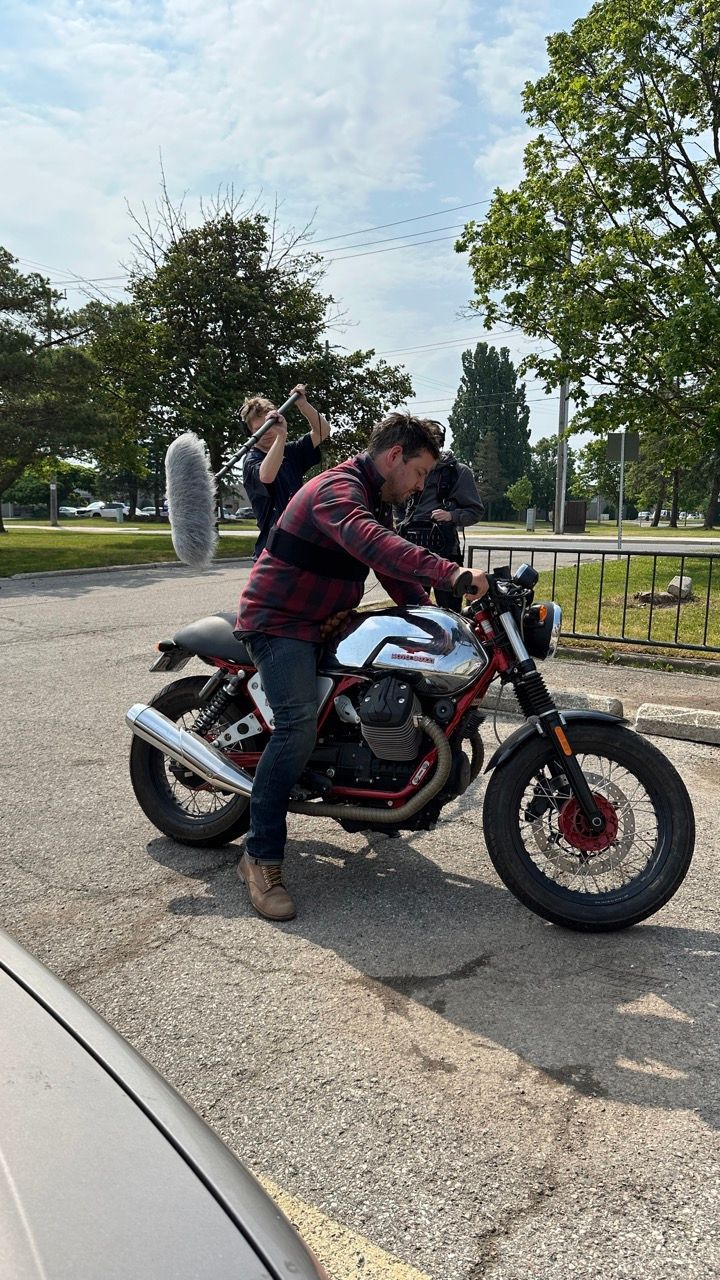 A man is riding a motorcycle in a parking lot.
