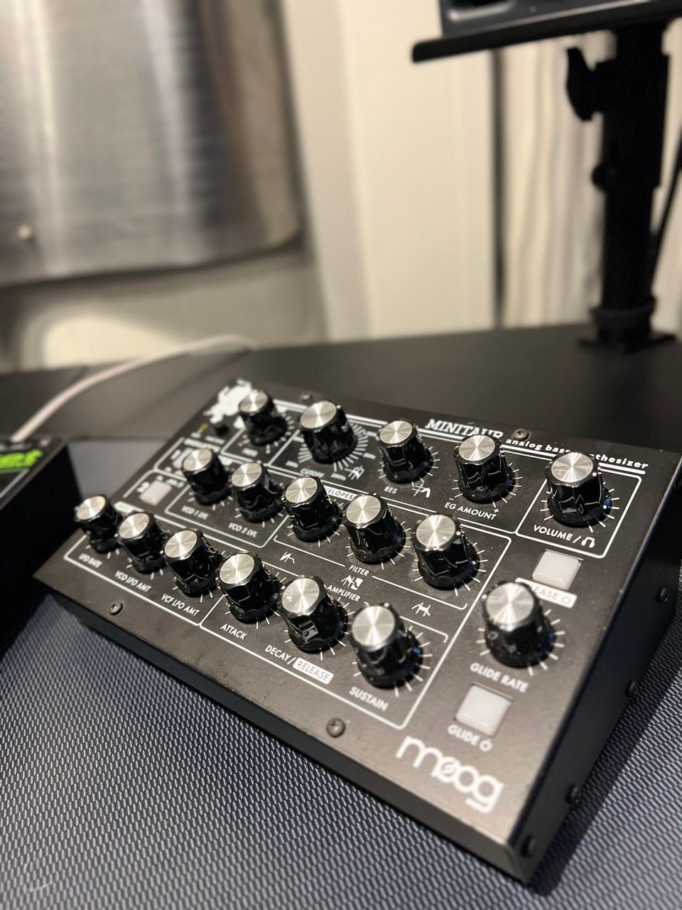 Black Moog synthesizer with multiple knobs on a desk.