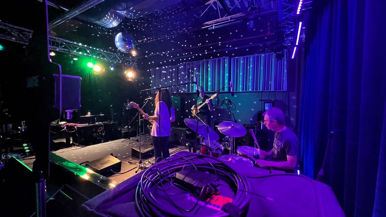 A group of people are playing instruments on a stage in a dark room.