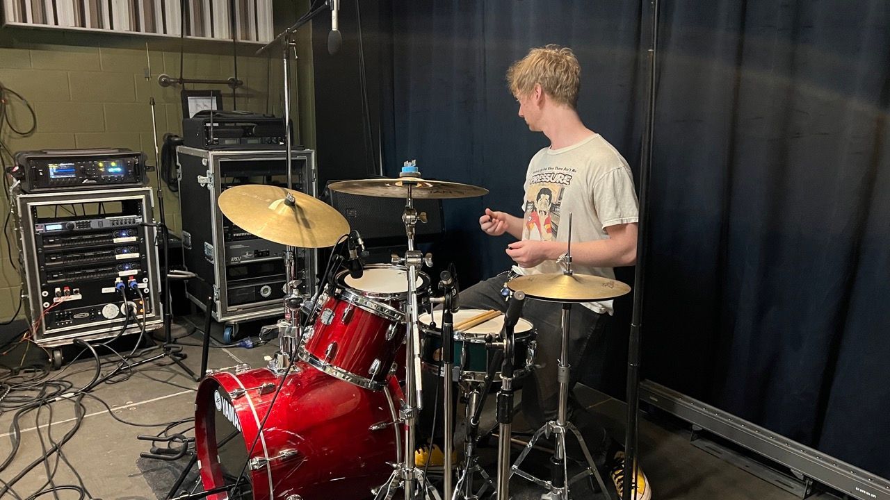 A young man is playing drums in a room.