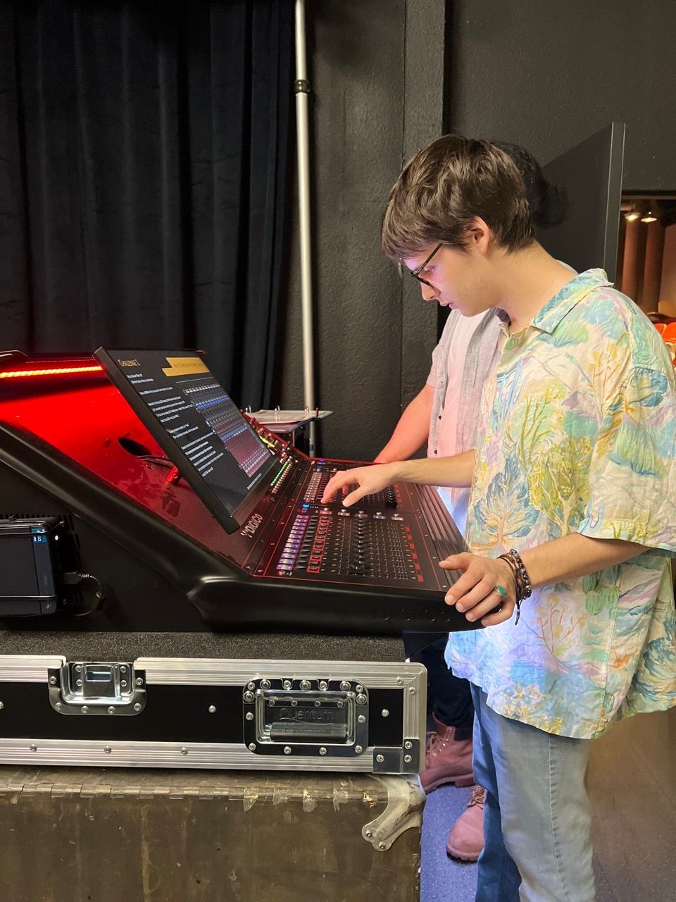 A man in a floral shirt is working on a keyboard