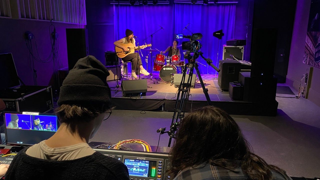 A man and a woman are watching a band perform on stage.