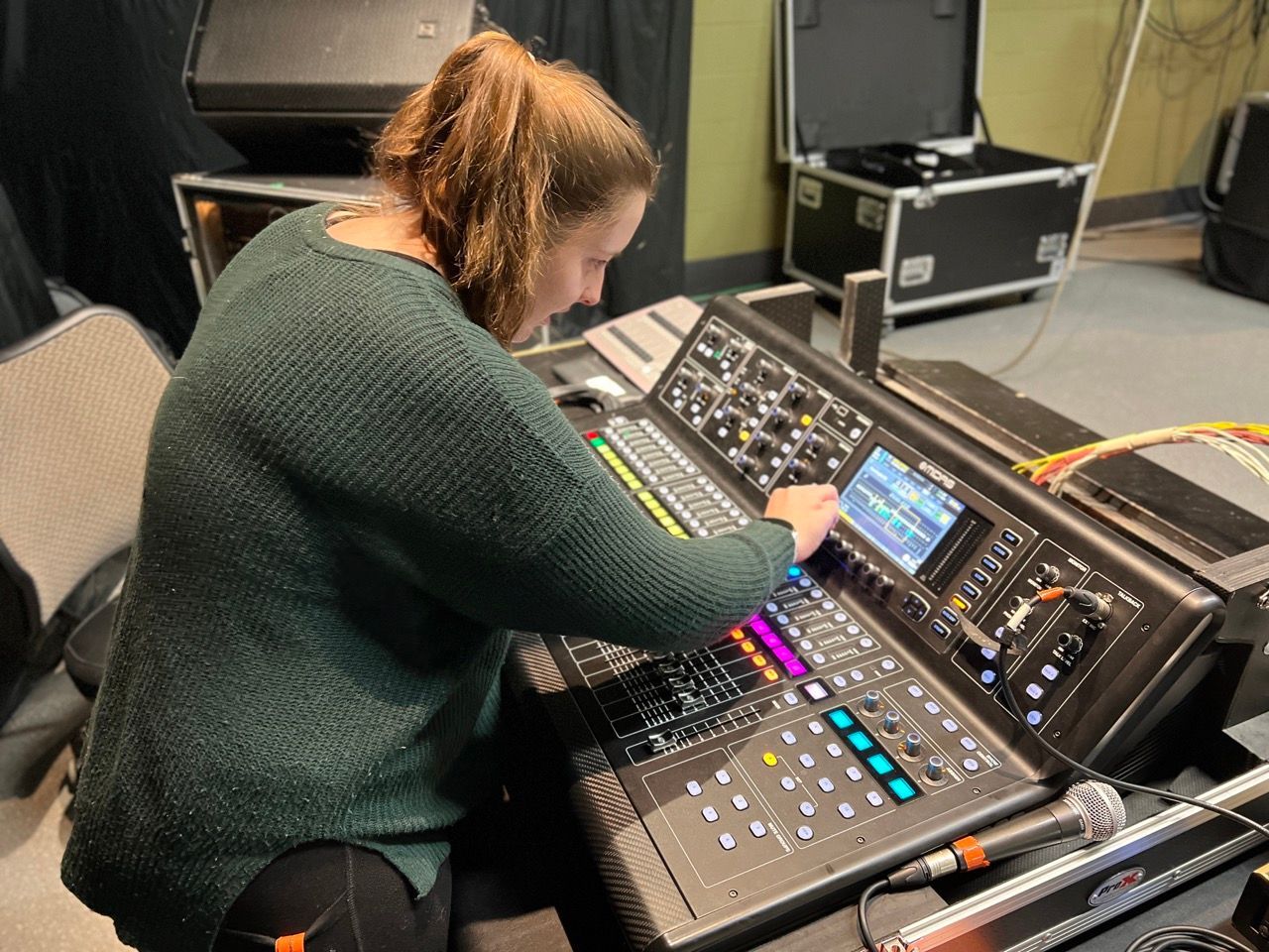 A woman is sitting in front of a mixer in a room.