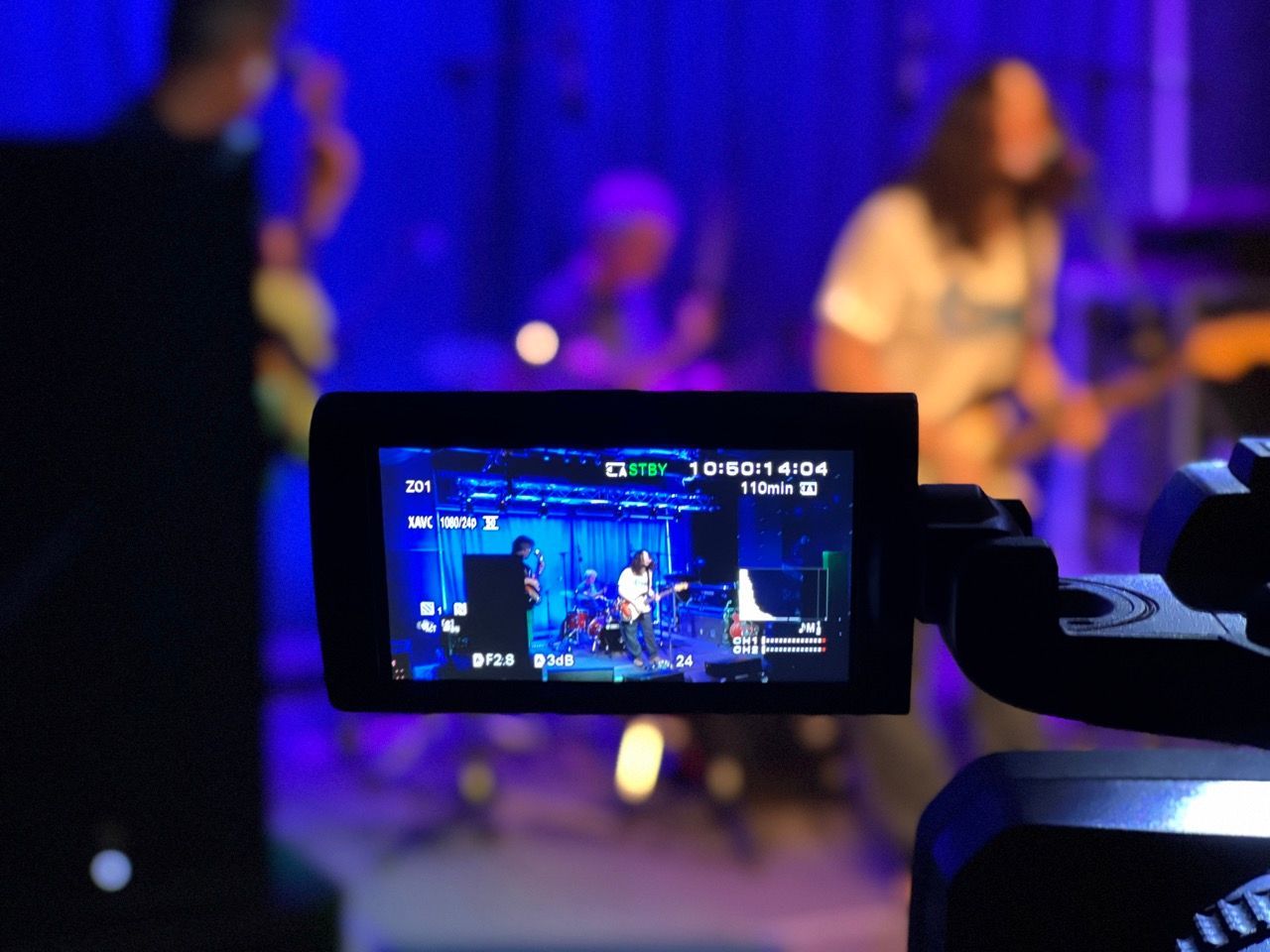 A video camera is recording a band on stage