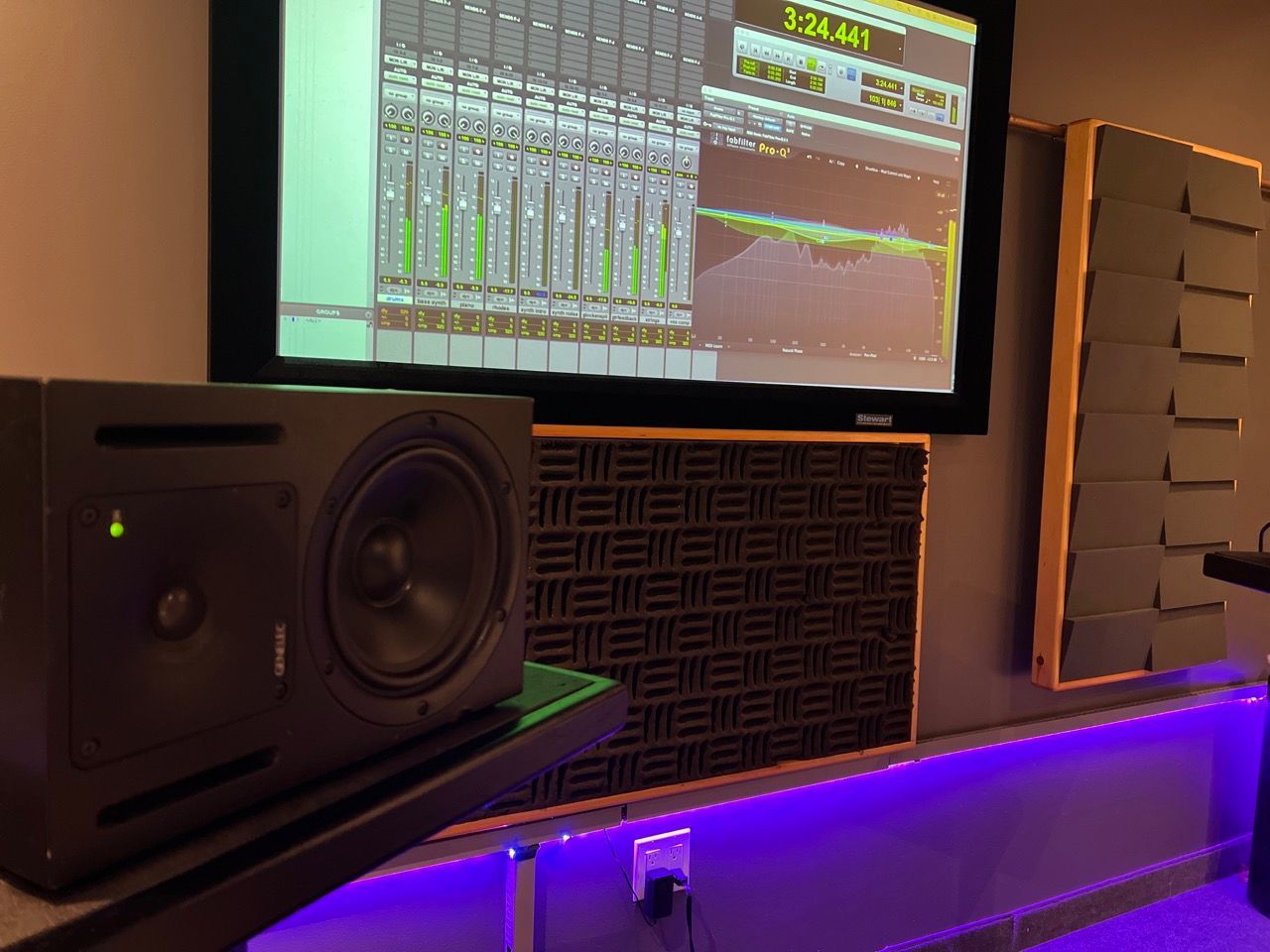 A recording studio with a monitor , speakers , and a computer screen.