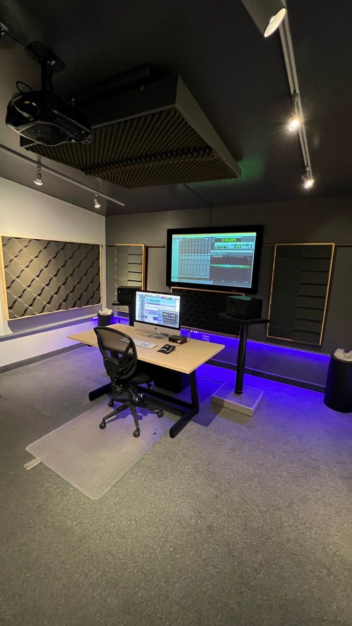 A room with a desk , chair , computer and television.