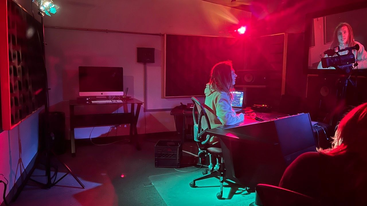 A woman is sitting at a desk in a dark room with red and green lights.