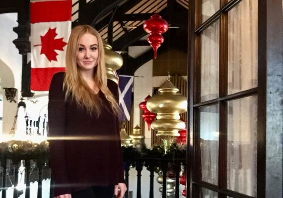 A Hayley Henrikson standing in front of a Canadian flag.