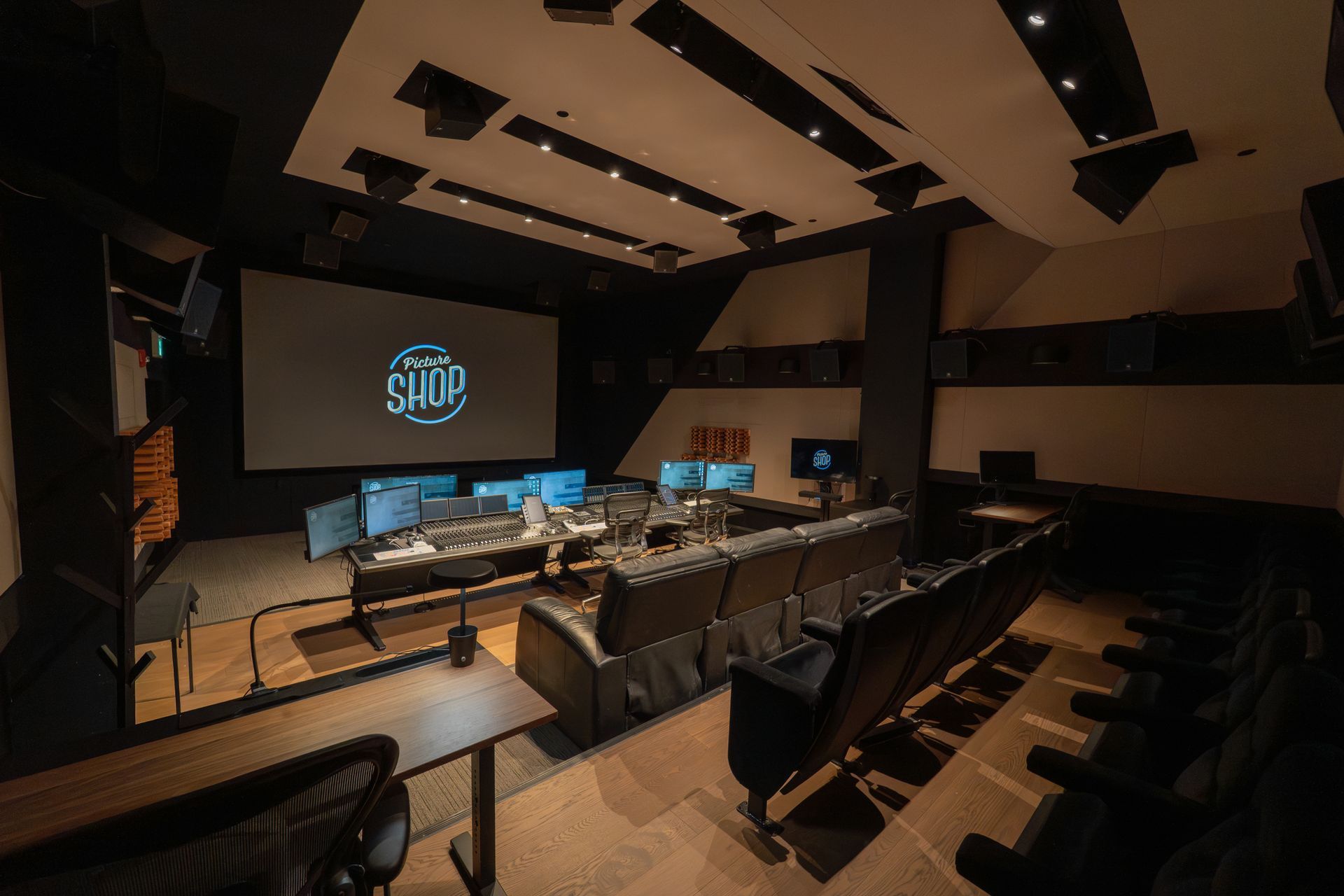 Empty lecture hall with rows of seats, a stage, and a large screen displaying a logo
