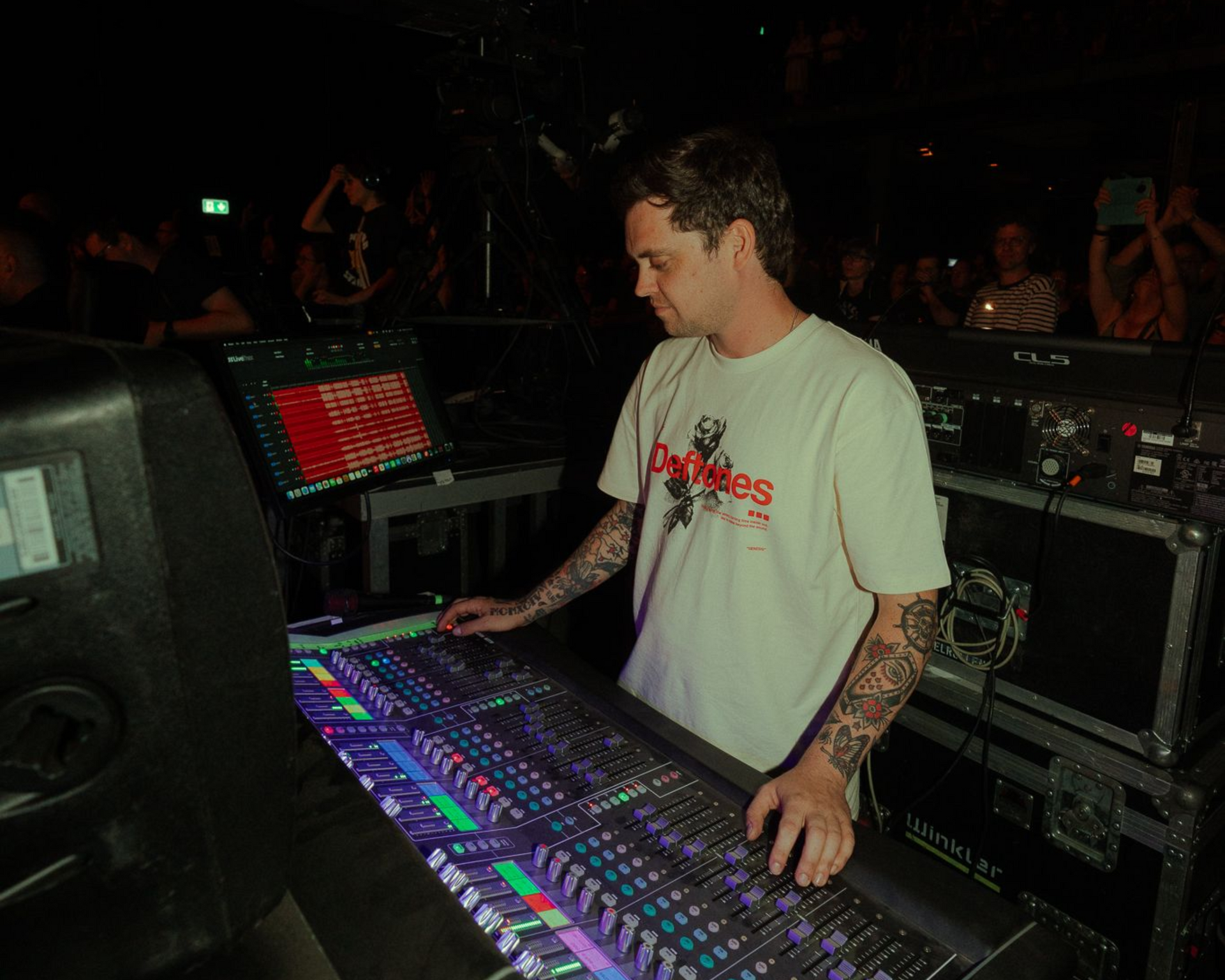 Michelle seated at a studio mixing desk facing large monitors in a modern recording room
