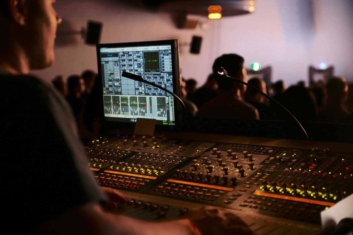 A man is working on a sound board in front of a crowd.