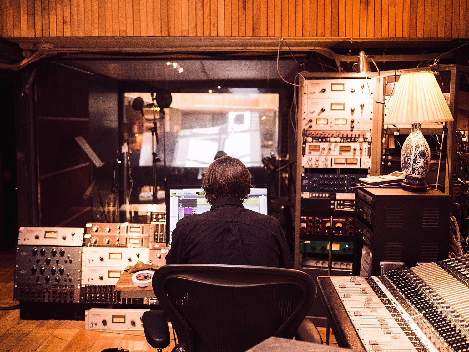 A man is sitting in front of a computer in a recording studio