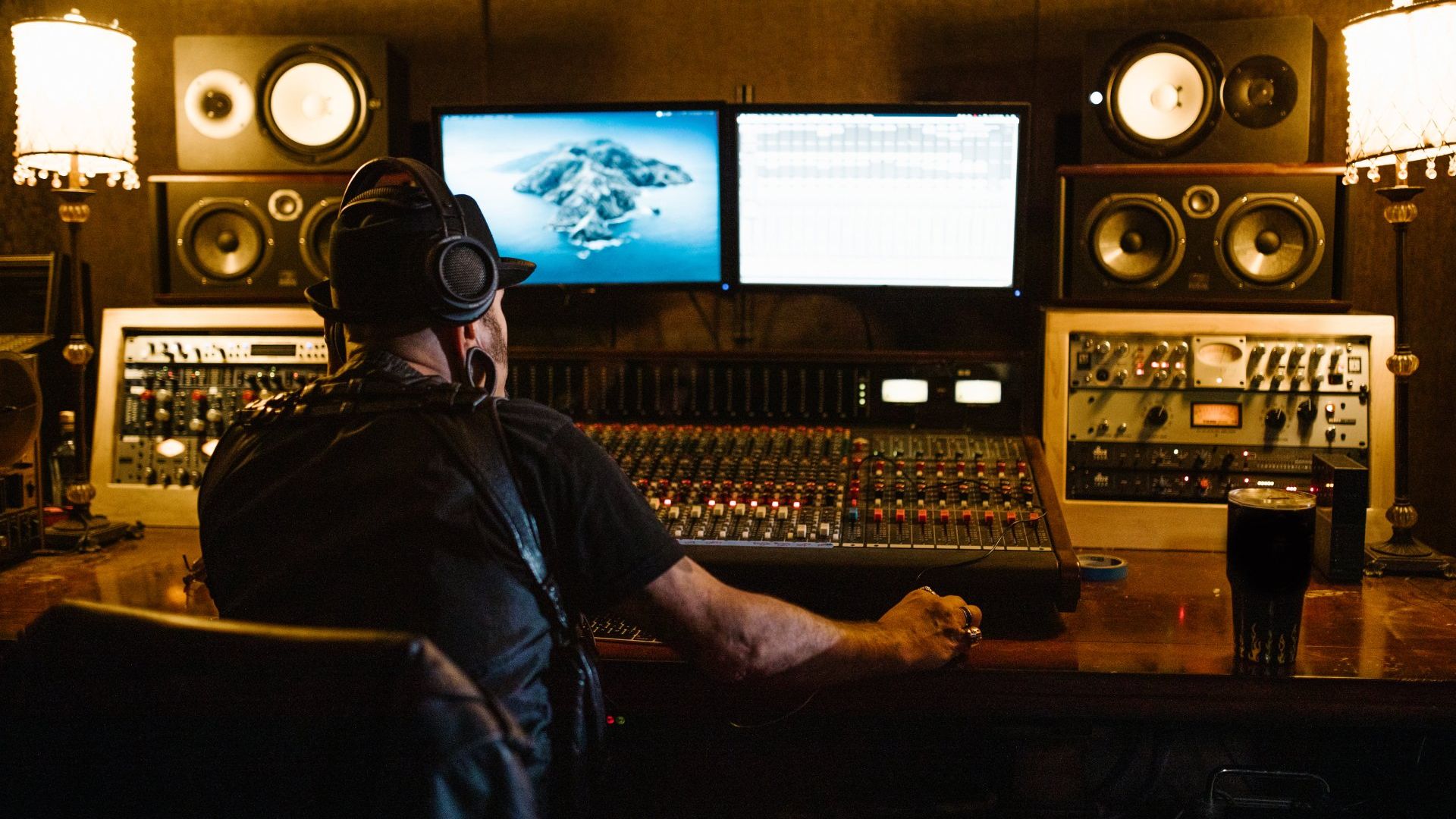 A man is sitting at a desk in a recording studio.