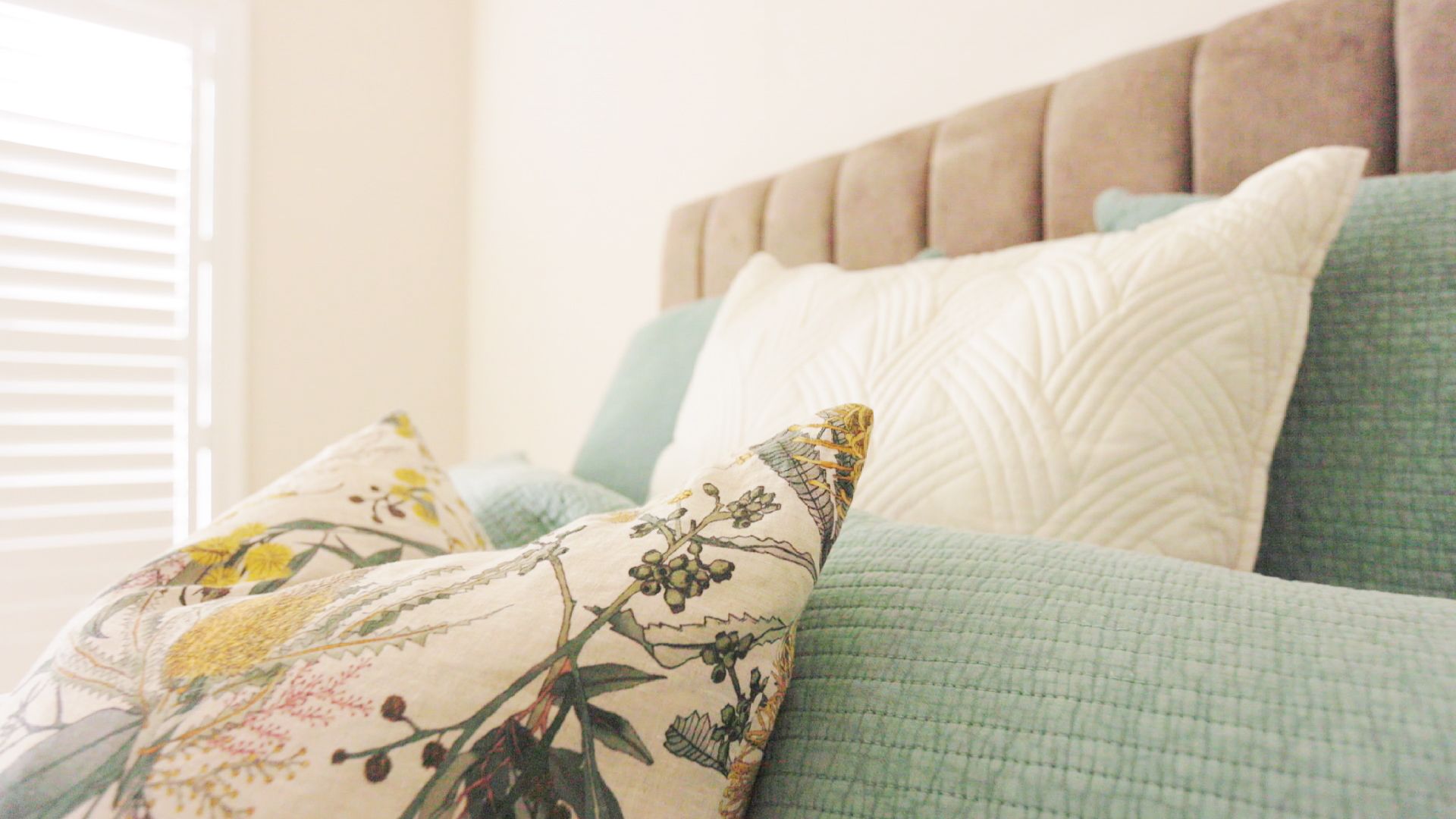 Bed With Light Blue and Patterned Pillows Against a Beige Headboard — Evolution Building Group Dapto, NSW