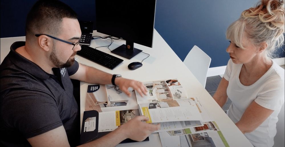 A Man and A Woman Are Sitting at A Table Looking at A Magazine — Evolution Building Group Dapto, NSW