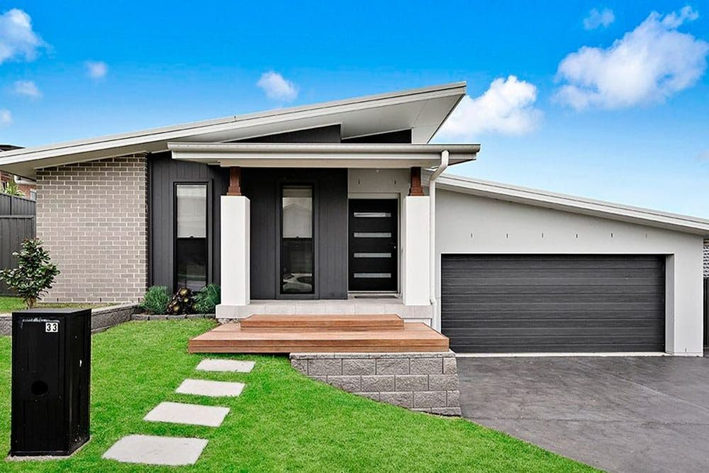 A Modern House with A Black Garage Door and A Black Mailbox — Evolution Building Group Dapto, NSW