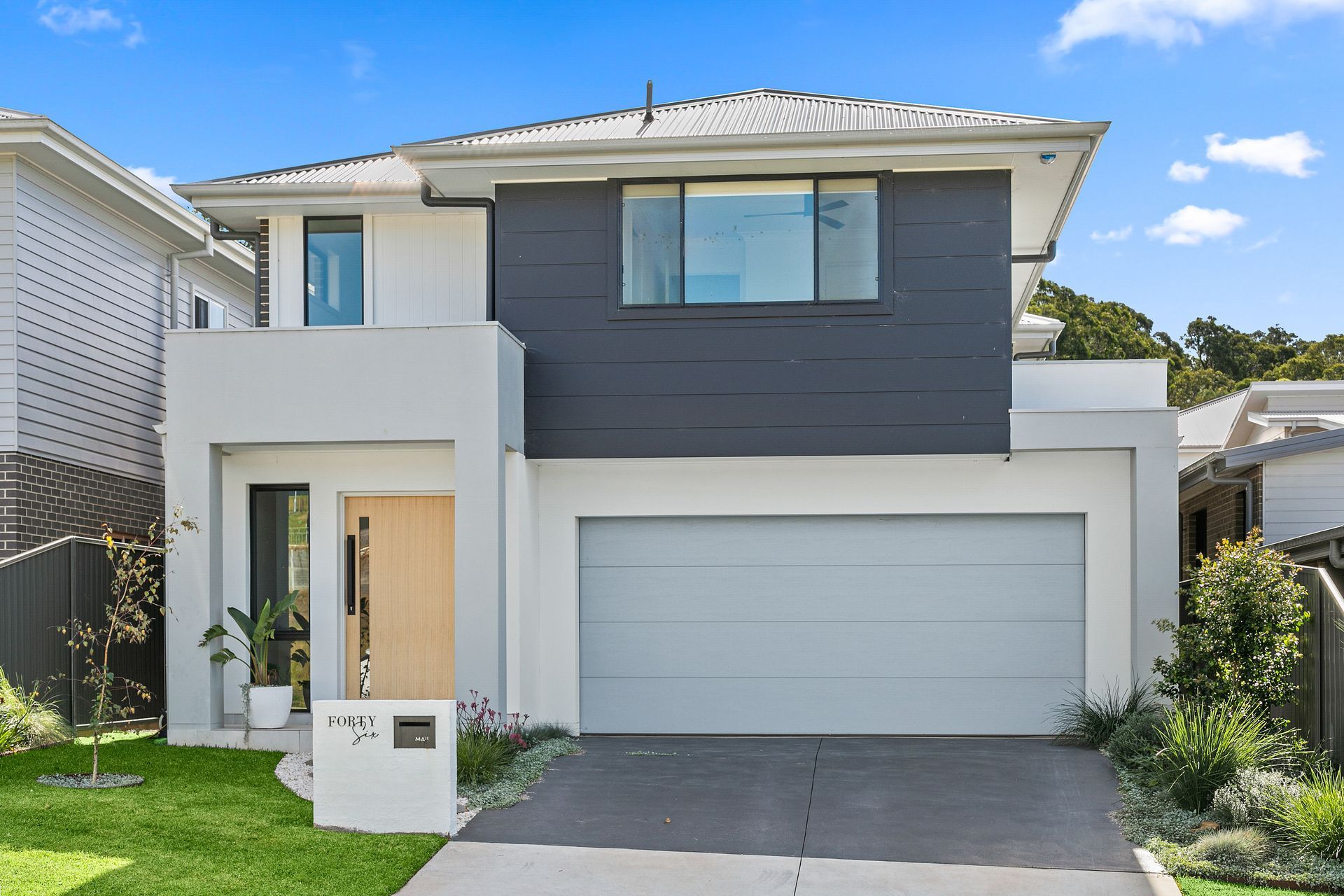 Modern two-story house with white and dark grey exterior, garage door, and lawn in front — Evolution Building Group In Bowral, NSW