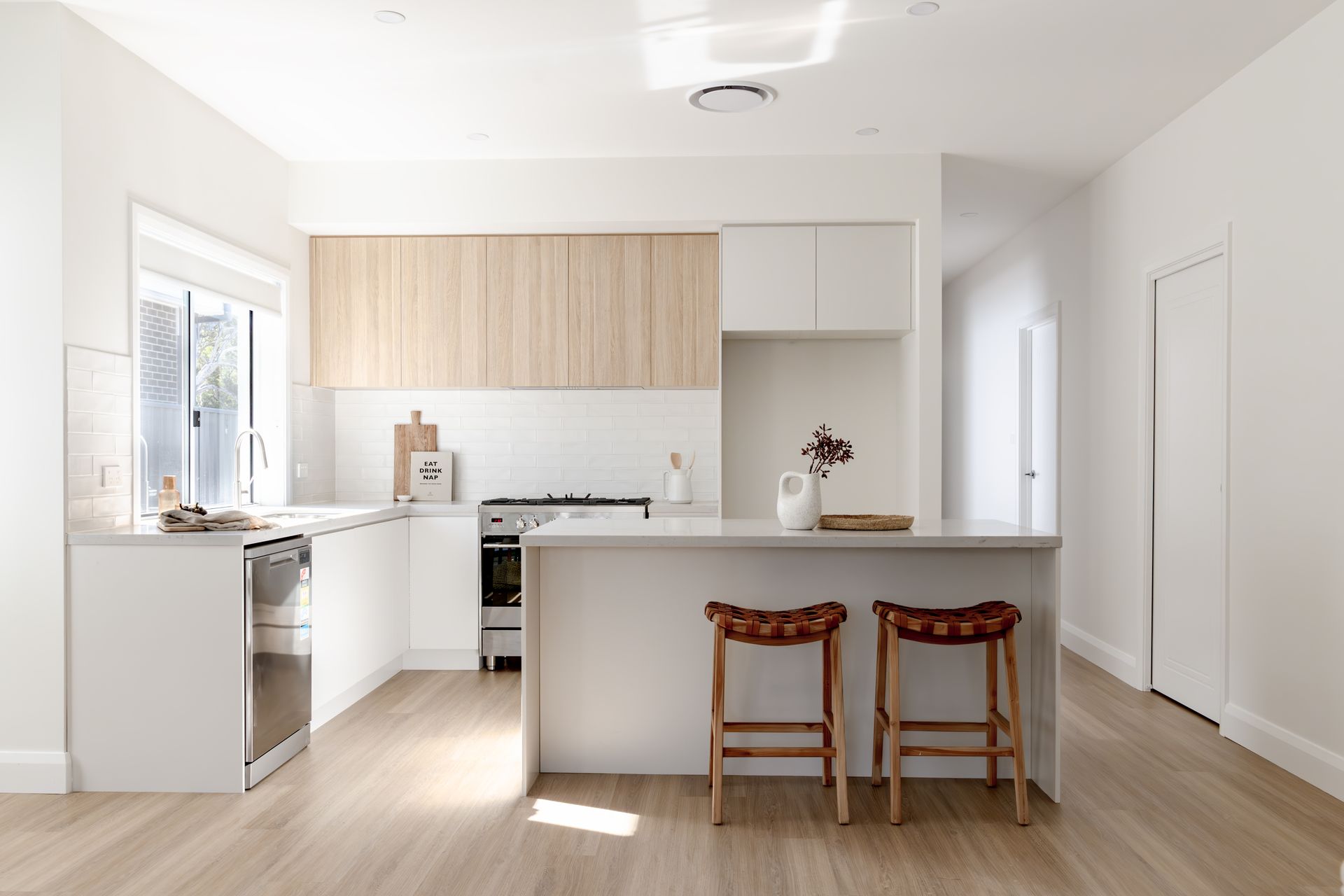 Modern White Kitchen With Light Wood Cabinets, Breakfast Bar — Evolution Building Group in Wollongong, NSW
