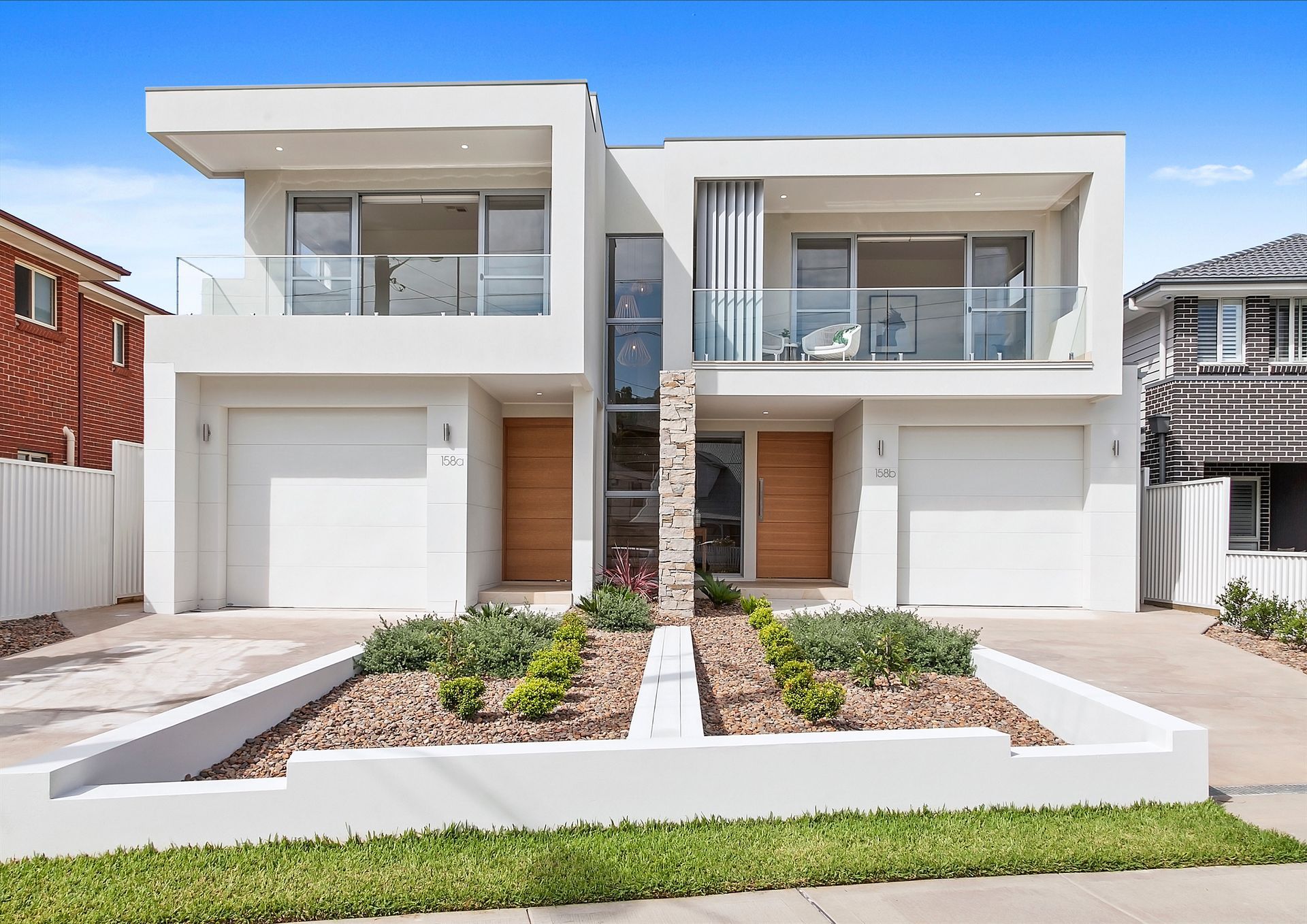 Modern White Duplex with Glass Balconies, Wooden Doors — Evolution Building Group in Dapto, NSW