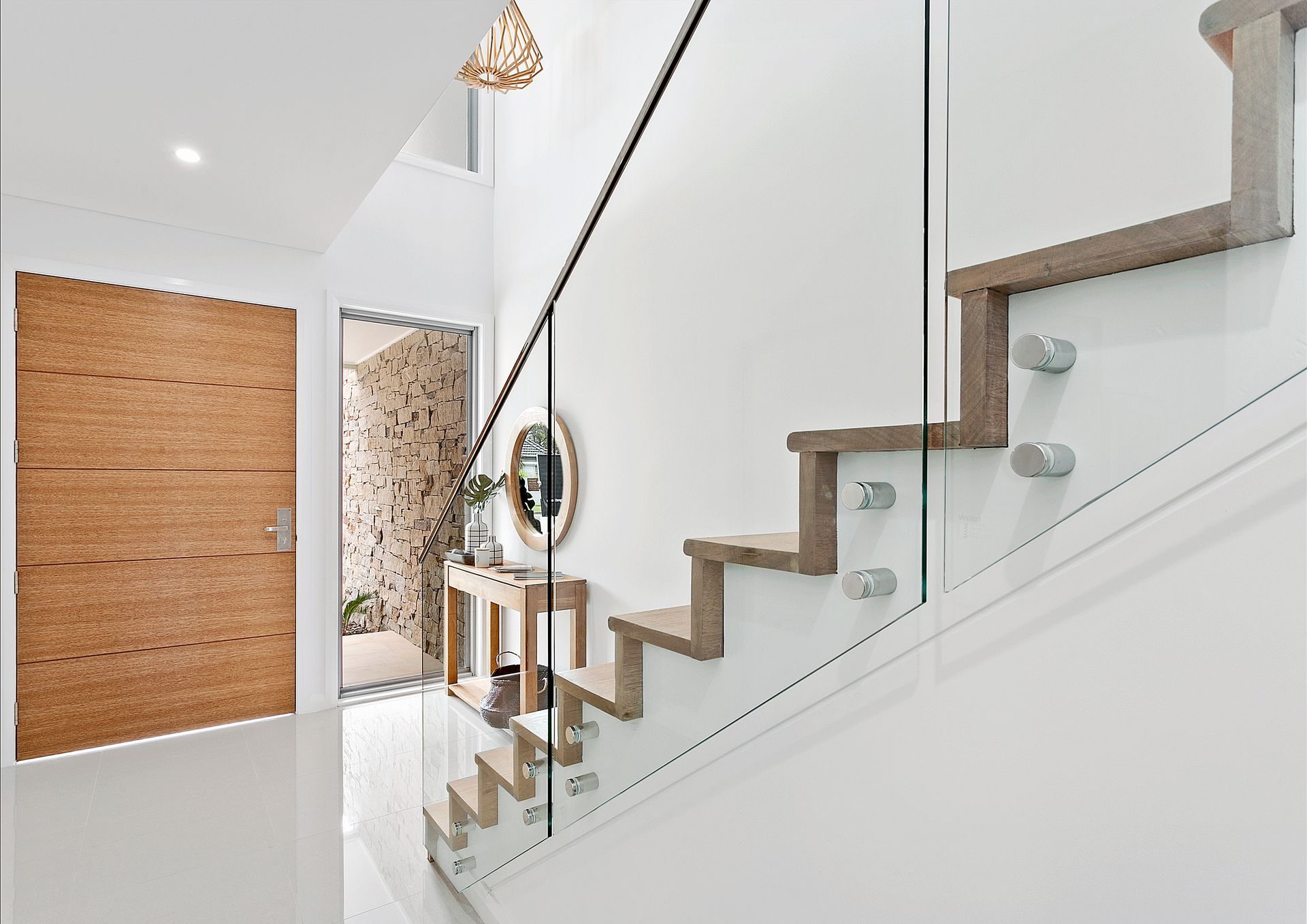 Interior view of a modern staircase with glass railing. Wooden steps and a light-coloured door are also visible  — Evolution Building Group In Berry, NSW