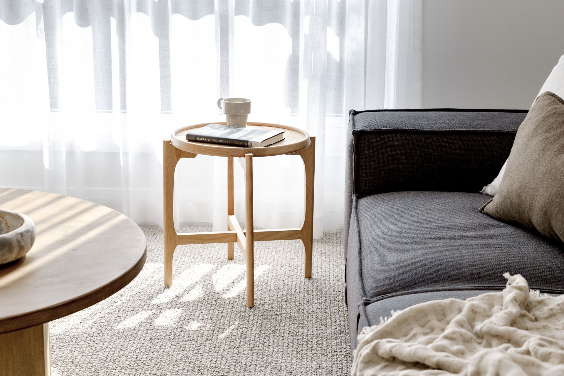 Wooden Side Table With a Book and Mug, Next to a Couch and Round Table — Evolution Building Group in Wollongong, NSW