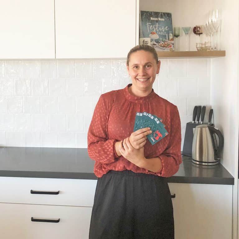 A Woman Is Standing in A Kitchen Holding a Fan of Cards — Evolution Building Group Dapto, NSW